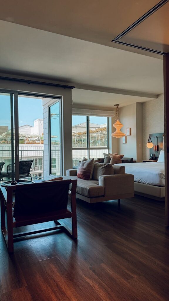 Cozy modern hotel room with large windows overlooking cityscape and stylish decor.