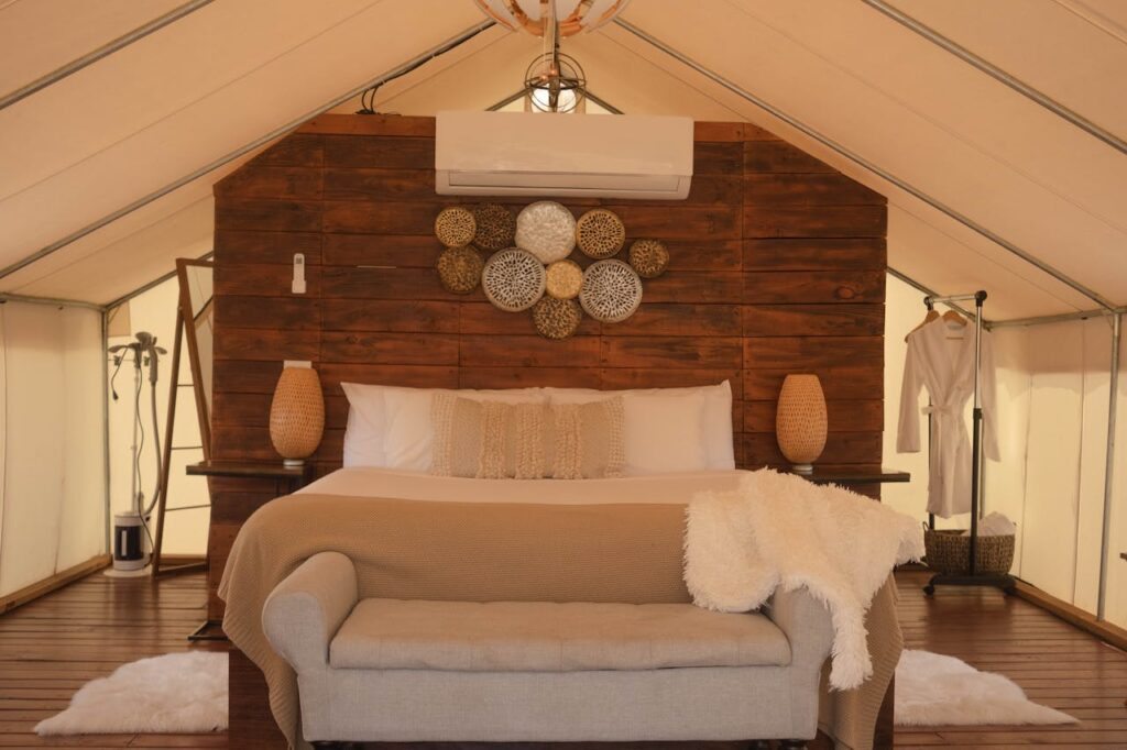 Elegant glamping tent featuring a beautifully designed bedroom with cozy textiles and rustic decor.
