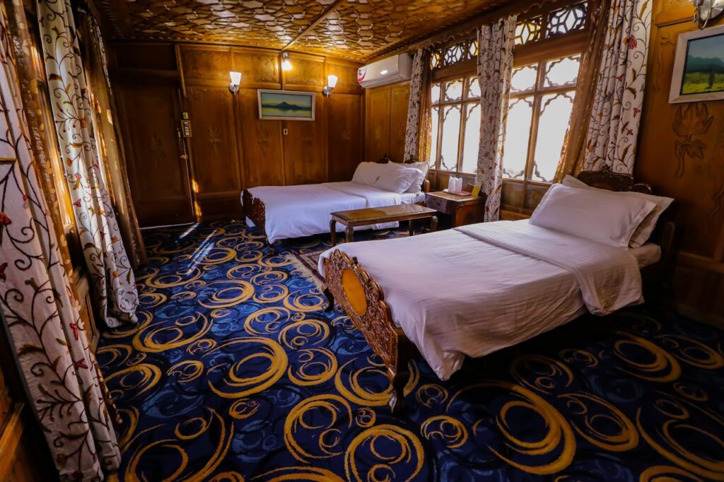 Elegant hotel room with wooden furnishings and twin beds, featuring artistic carpet and curtains for a cozy stay.